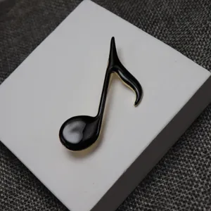 Detailed close-up view of a black enamel musical note brooch with elegant gold trim.