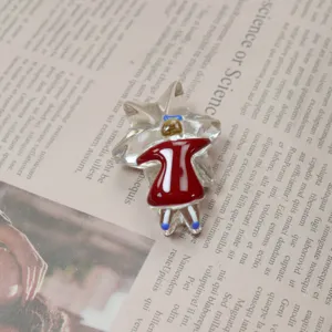 Close-up detail of the handmade glass star and red dress girl brooch against newspaper background.