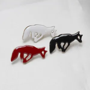 Detailed shot of three running animal enamel brooches in white, black and red colors.