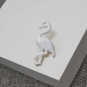 Vue detaillee du charmant brooch en email blanc flamant rose, accessoire elegante.
