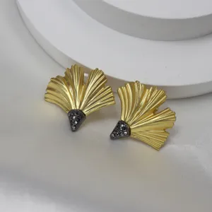 Close-up detail of vintage matte gold ginkgo leaf earrings featuring sparkling black crystal accents.