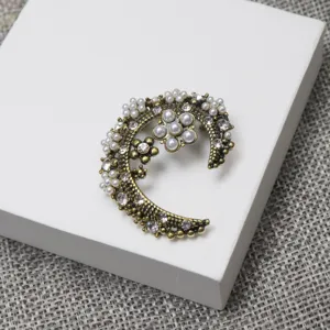 Vintage gold plated crescent moon pearl rhinestone brooch detail, elegant fashion accessory.