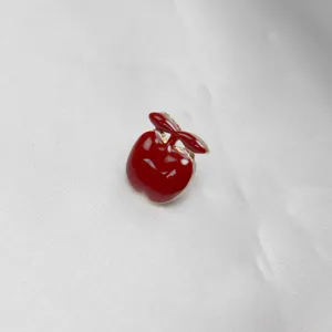 Dettaglio spilla smaltata mela rossa, simpatica spilla metallica da collo, accessorio borsa.