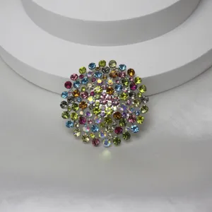 Gros plan d'une broche ronde vintage en strass avec cristaux colorés sur support argenté.