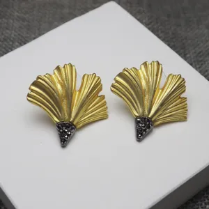 Close-up of vintage matte gold ginkgo leaf earrings with dark rhinestone details.