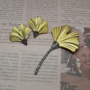 Vintage matte gold ginkgo leaf brooch and earrings set with dark rhinestones detail.