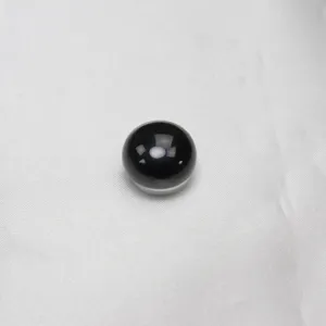 Black agate magnetic brooch detail view, smooth surface round bead on white fabric background.