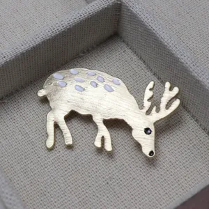 Spilla a forma di cervo dorata con macchie di smalto bianco ed eleganti dettagli chic.