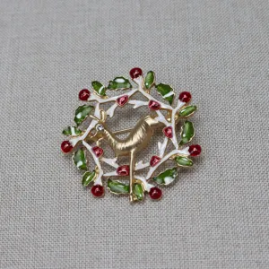 Nahaufnahme der Vintage Weihnachts-Hirsch-Brosche mit grünen Blättern und roten Beeren.