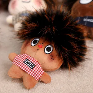 Close-up detail of cute plush doll pendant with fluffy hair and checkered apron design.