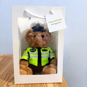 Detailed close-up view of the cute police teddy bear wearing a uniform inside gift bag.