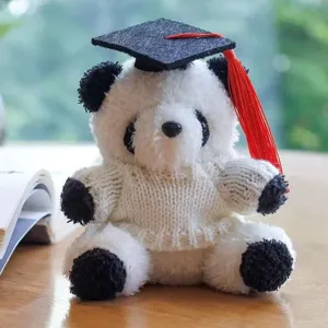 Primo piano di un simpatico panda di peluche con berretto di laurea e maglione lavorato a maglia.