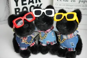 Simpatico cucciolo di peluche nero con occhiali da sole colorati e camicia di jeans dettaglio.