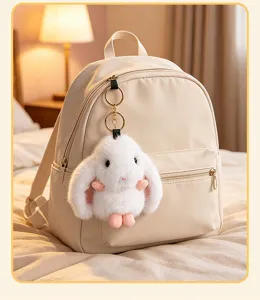 Cute lop-eared rabbit plush toy keychain pendant hanging on a stylish beige backpack.