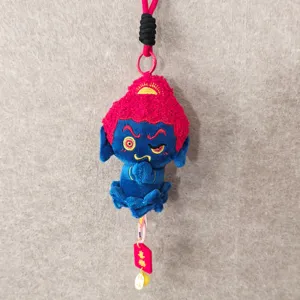 Detail shot of the cute blue Buddha plush pendant with red hair, hanging charm and soft texture.