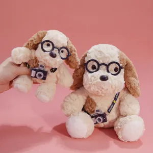 Close-up detail of cute plush puppy toy with round glasses and mini camera pendant, soft fabric.