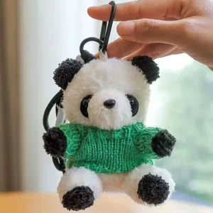 Delizioso portachiavi panda in peluche con maglione lavorato a maglia verde, primo piano.