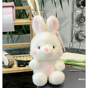 Gros plan détaillé d'un adorable lapin en peluche blanche assis doucement sur un bureau.