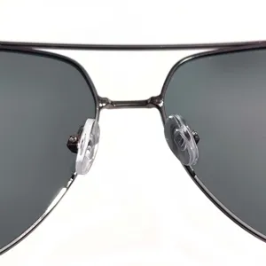 Detailed view of metal aviator sunglasses bridge and nose pads, premium dark polarized lenses.