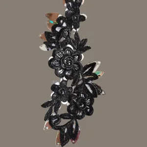 Vista detallada de bordado de encaje negro con lentejuelas brillantes y detalles de strass.