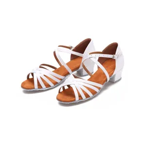 Detailed view of children's white satin latin dance shoes with low heel and cross straps.