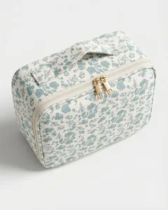 Closeup of the elegant blue floral makeup storage bag showing fine fabric and double gold zippers.