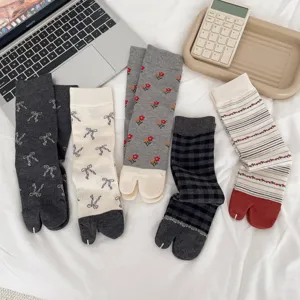 Close-up view of split-toe socks featuring cute floral, bow, and plaid patterns in a cozy setup.