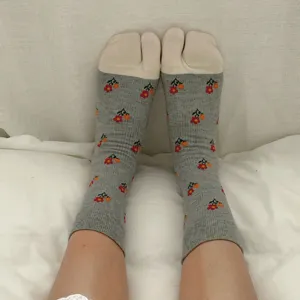 Close-up of women's two-toe split socks with cute floral pattern, grey mid-calf style detail.