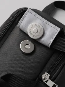Detailed close-up of the metal magnetic snap and textured fabric on the black travel toiletry bag.