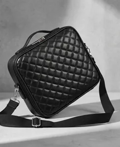 Close-up detail of black quilted cosmetic bag with sturdy handle, adjustable strap and zipper.