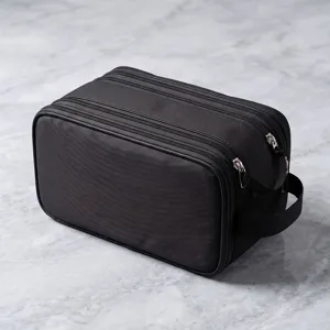 Black travel toiletry bag detail view, multi-compartment zipper storage pouch for men shaving.