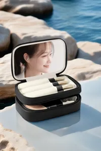 Vue de détail d'un étui à cosmétiques portable noir avec miroir et pinceaux de maquillage.