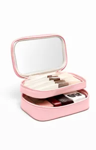 Trousse de maquillage de voyage rose à double compartiment avec miroir et accessoires.