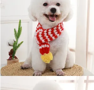 Closeup of red white knit pet scarf with yellow pompom, soft warm winter wool accessory.