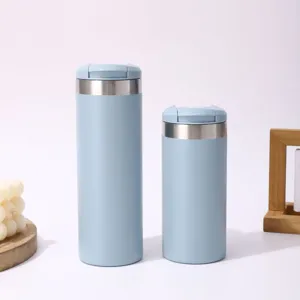Gros plan de deux tasses isothermes en acier inoxydable bleu clair avec couvercle.
