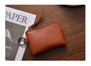 Detail view of mini brown leather coin purse, portable compact zipper design with keychain hook.