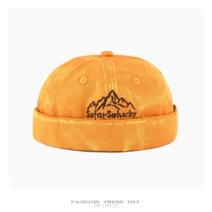Detailed view of washed denim docker hat with embroidered mountain and custom slogan text.