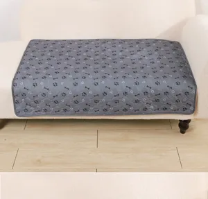 Grey washable pet pee pad detail showcasing cute paw and bone patterns on soft sofa fabric.