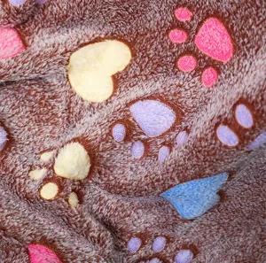 Close-up detail of soft brown fleece pet blanket featuring colorful cute paw prints.