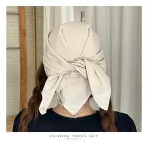 Detail view of beige headscarf hat with tied back design, soft fabric, lifestyle shot.