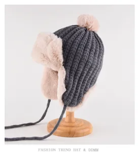 Grey knitted trapper hat with pink faux fur earflaps and pom pom for winter warmth.