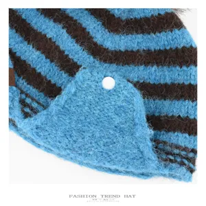 Close-up detail view of the blue and brown striped winter knit hat with cozy soft texture.