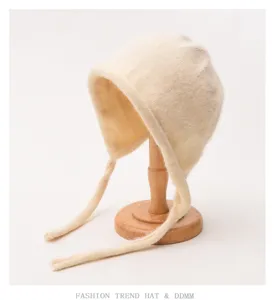 Cute plush bonnet hat with ear flaps and straps, soft knitted texture, cozy winter accessory detail.