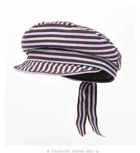Detailed view of brown and white striped newsboy cap, flat top beret style with hanging ribbon.