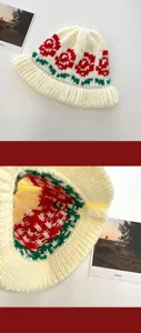 Detailed close-up of handmade knitted bucket hat featuring elegant red rose and green leaf patterns.