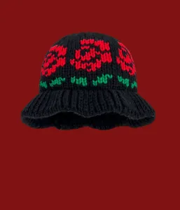 Detail view of the black knit bucket hat featuring a charming red rose and green leaf knit pattern.