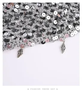 Gray crochet sequin beanie hat detail showing knit texture and metal charm decorations.