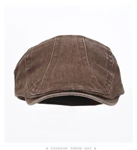 Close-up detail of the brown washed denim flat cap showing textured vintage fabric and stitching.