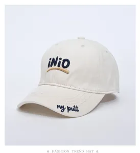 Detailed view of the beige cotton baseball cap featuring front embroidery and curved brim.