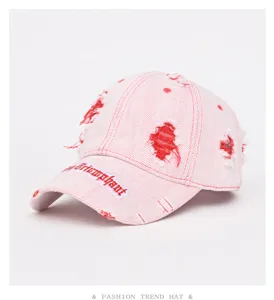 Berretto da baseball in denim rosa effetto used con ricami rossi, stile streetwear.